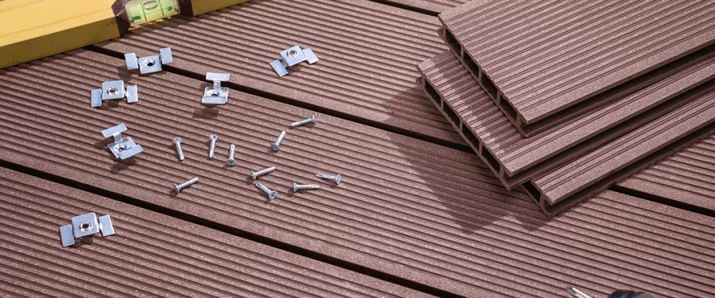 Composite decking surface with installation clips, screws, and level tool during setup