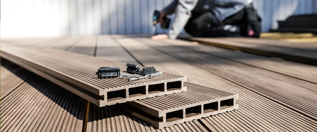 Close-up of composite decking boards with fasteners and tools during installation process