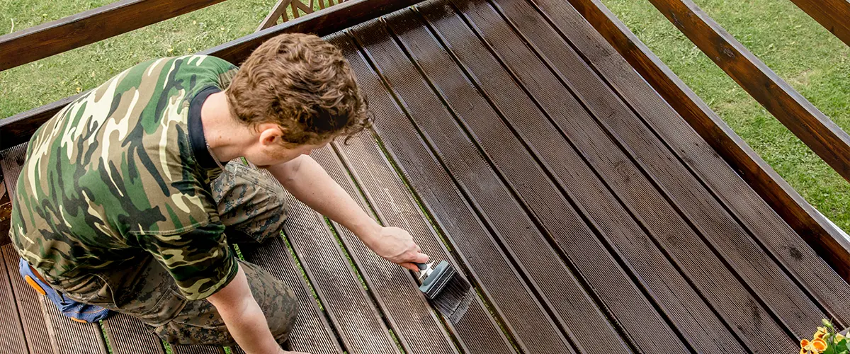 Person applying stain to enhance deck color and texture