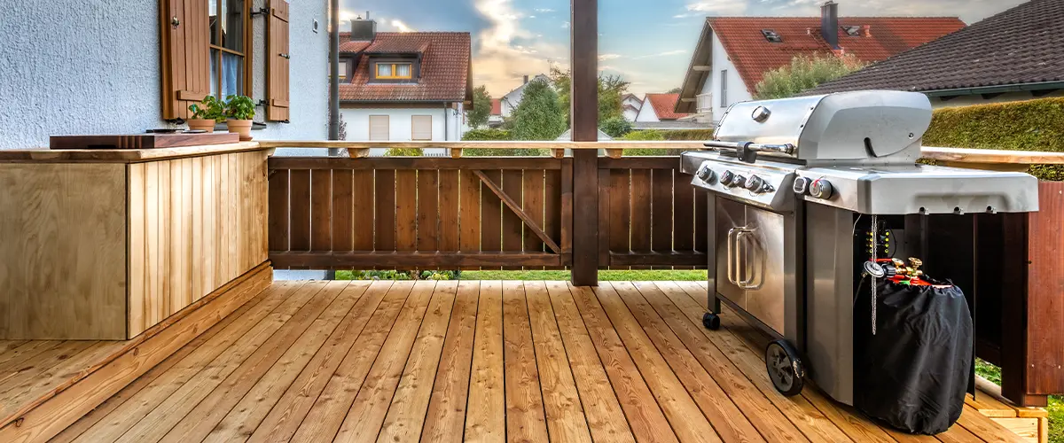 Charming backyard patio with wooden deck, modern grill, and outdoor kitchen area, ideal for al fresco dining and summer barbecues.