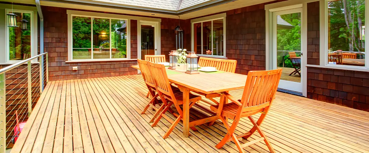 Deck addition in Blue Bell, PA featuring spacious wooden patio with outdoor dining set, surrounded by large windows and scenic views.