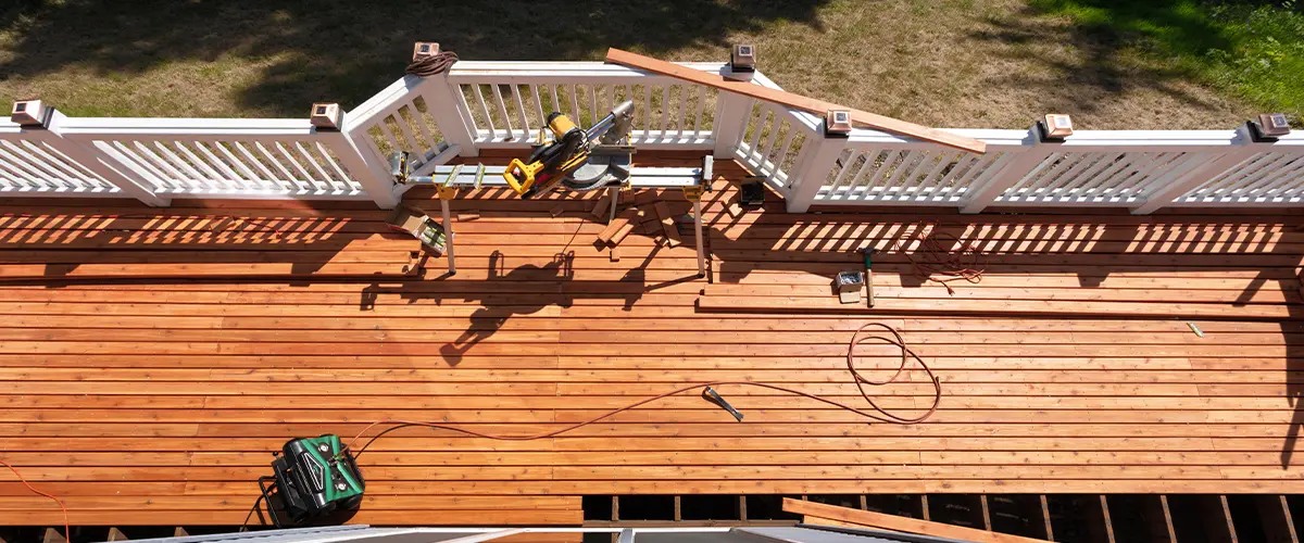 Aerial view of a deck repair project with tools like a saw and drill on the wooden surface