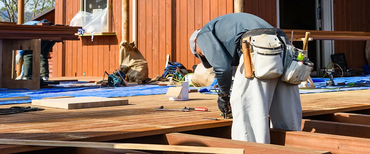 Construction worker building a wooden deck on a residential property