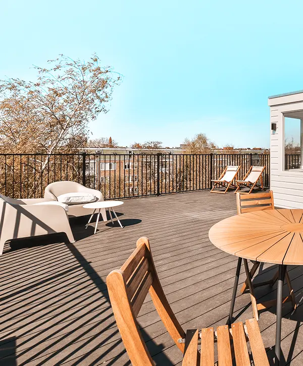 Rooftop deck with a small seating area and a round wooden table under a clear sky