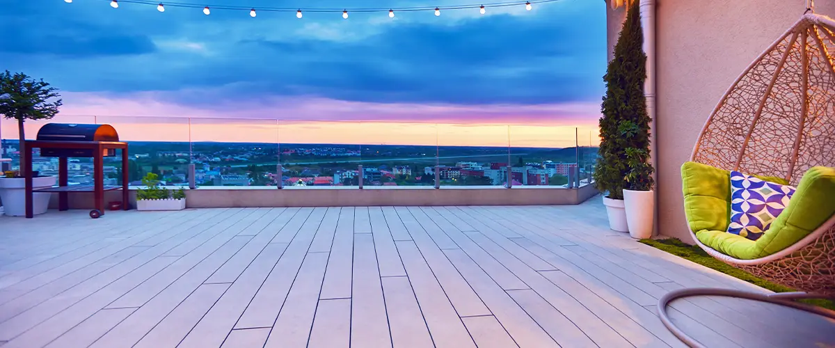 Rooftop deck at sunset with string lights, cozy seating, and panoramic city views.