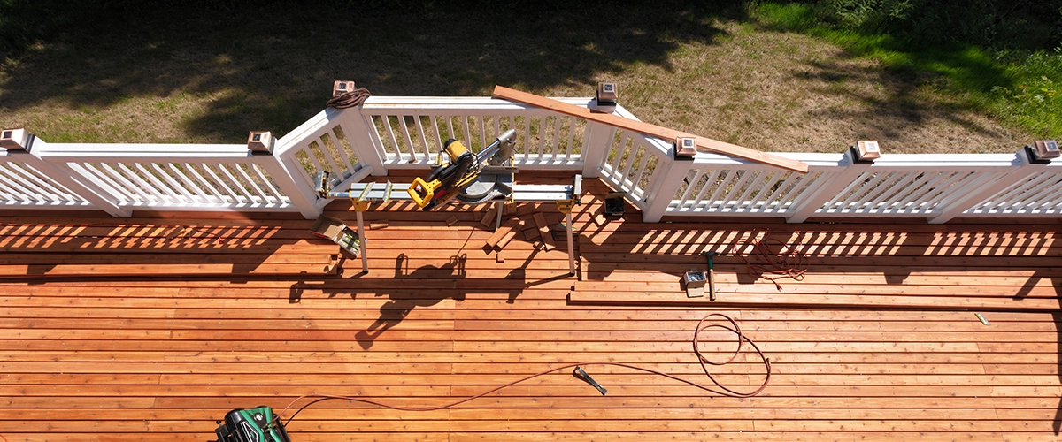 A charming wooden deck with a natural stain, complete with cozy outdoor furniture, railings by Deck Builder Company in Gladwyne PA